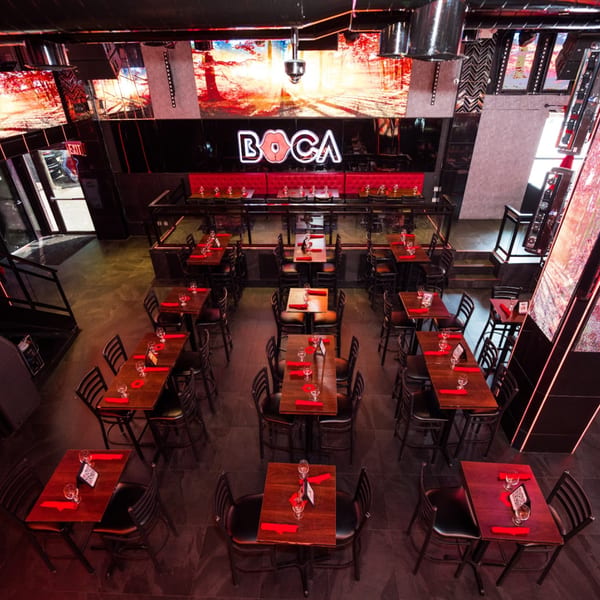 Overhead view of Boca Restaurant Lounge, featuring red-accented tables, black chairs, and large screens.