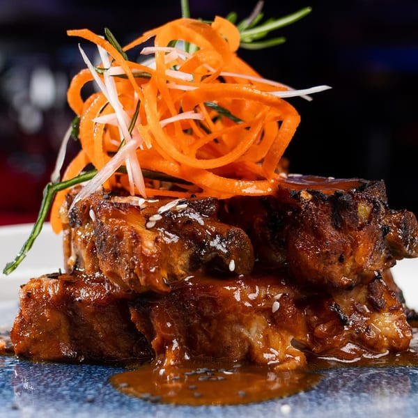 Close-up of Boca Restaurant Lounge's Latin-American ribs, glazed in sauce and topped with shredded carrots and herbs.